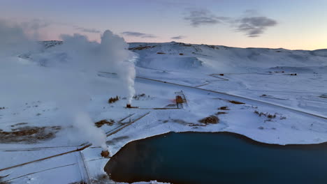 White-steam-comes-from-one-of-the-chimneys-of-a-geothermal-plant-in-the-snowy-Icelandic-landscape