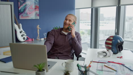 smiling man chatting smartphone in work room close up. manager listening client