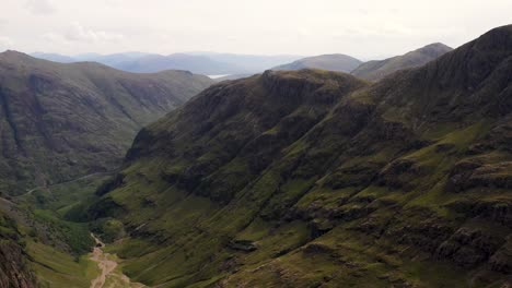 A-smooth-and-dramatic-aerial-shot-travelling-down-a-majestic-mountain-valley,-in-the-Highlands-of-Scotland-|-The-Lost-Valley,-Glencoe,-Scotland-|-Shot-in-4k-at-30-fps