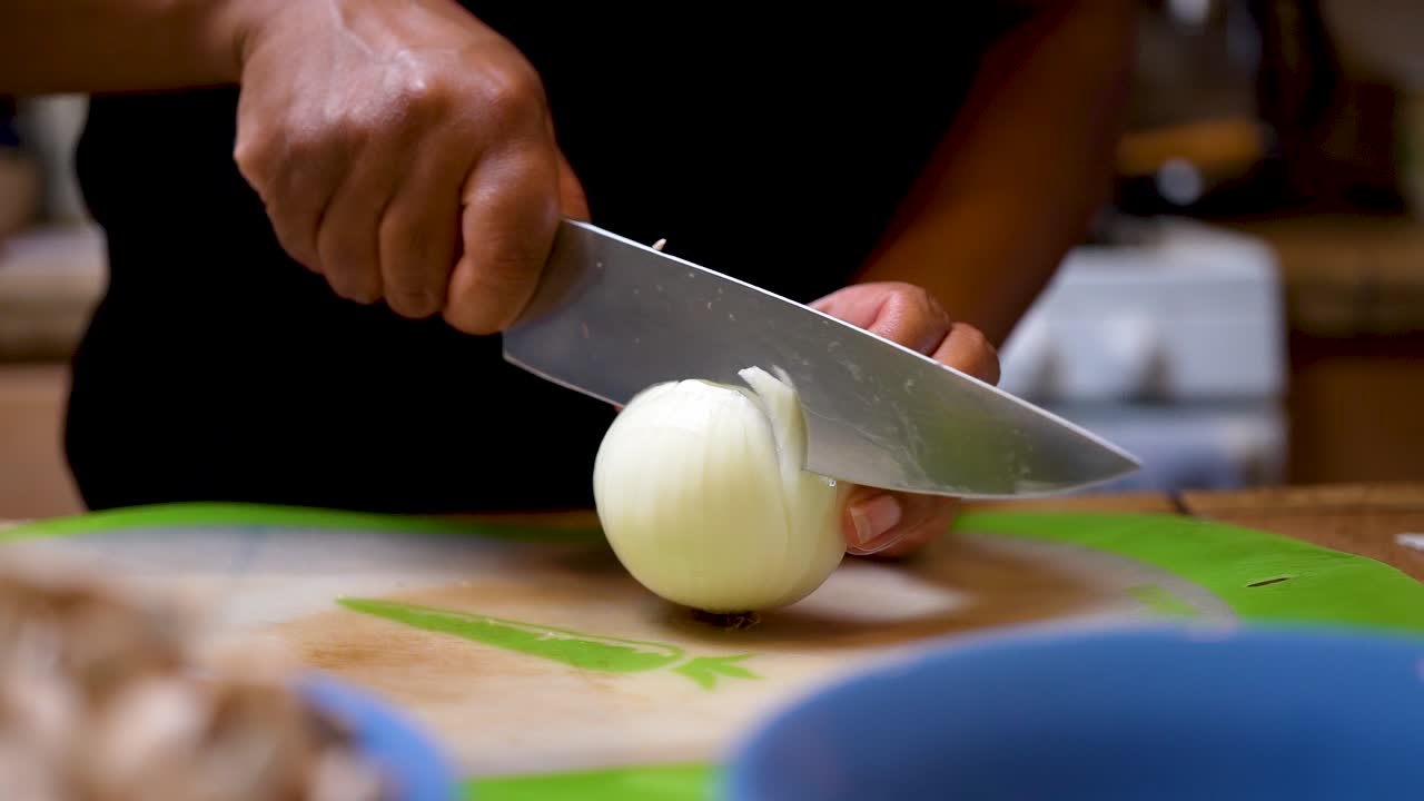 Slicing an onion for dicing with a focus pull to a bowl of sliced mushrooms - cinematic slow motion