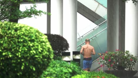 hombre desconocido corriendo sin camisa bajo la lluvia de hong kong, cámara lenta desde atrás