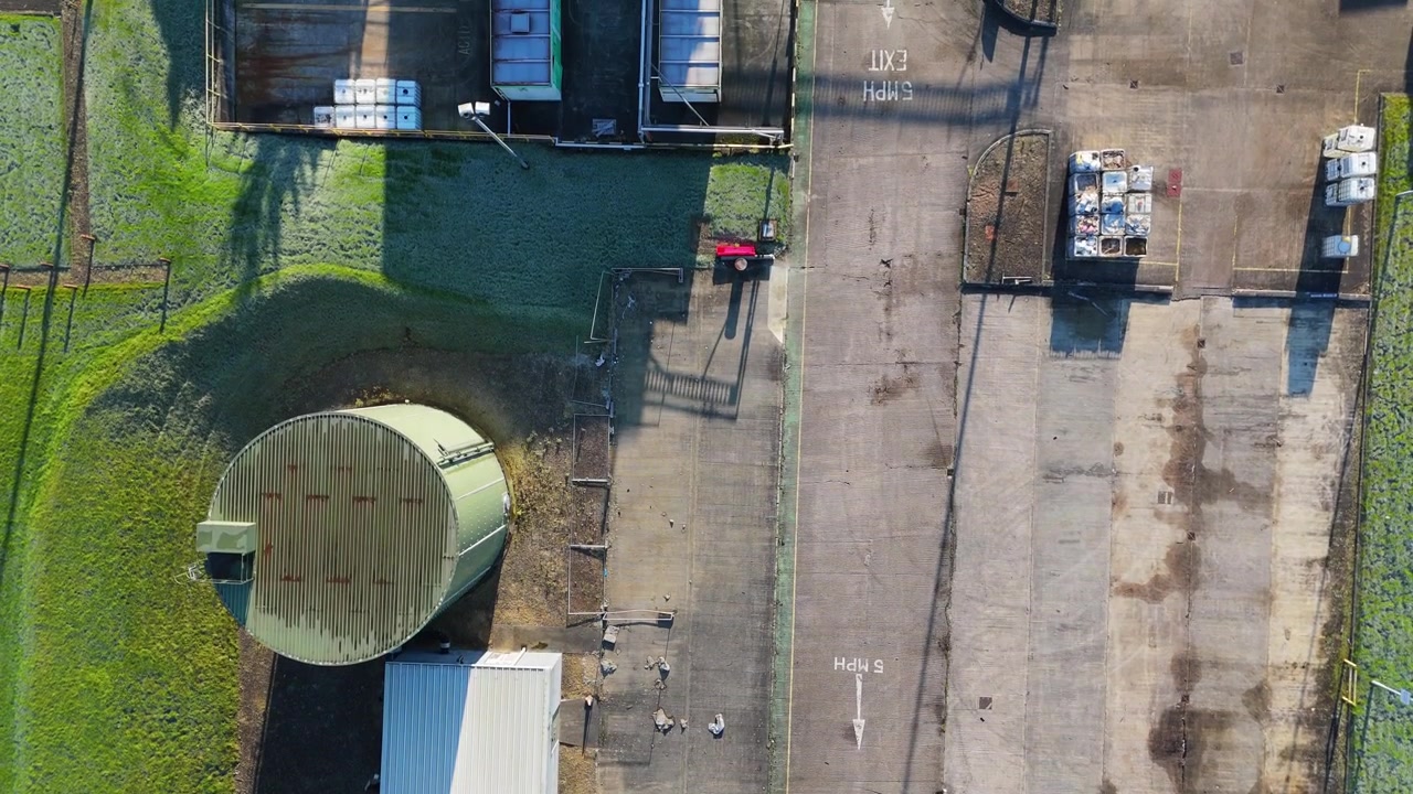Riprese aeree con drone dall'alto di un'area industriale e commerciale. Impianto di stoccaggio con scene mattutine di lavoratori e veicoli in movimento, con uomini al lavoro. Container e macchinari di un impianto chimico