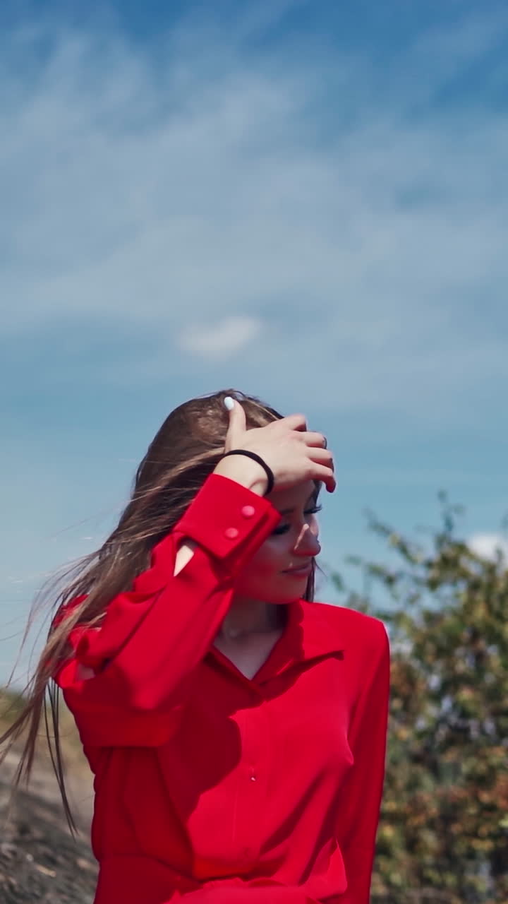 Woman posing on nature. Beauty woman in red dress outdoor. Vertical video