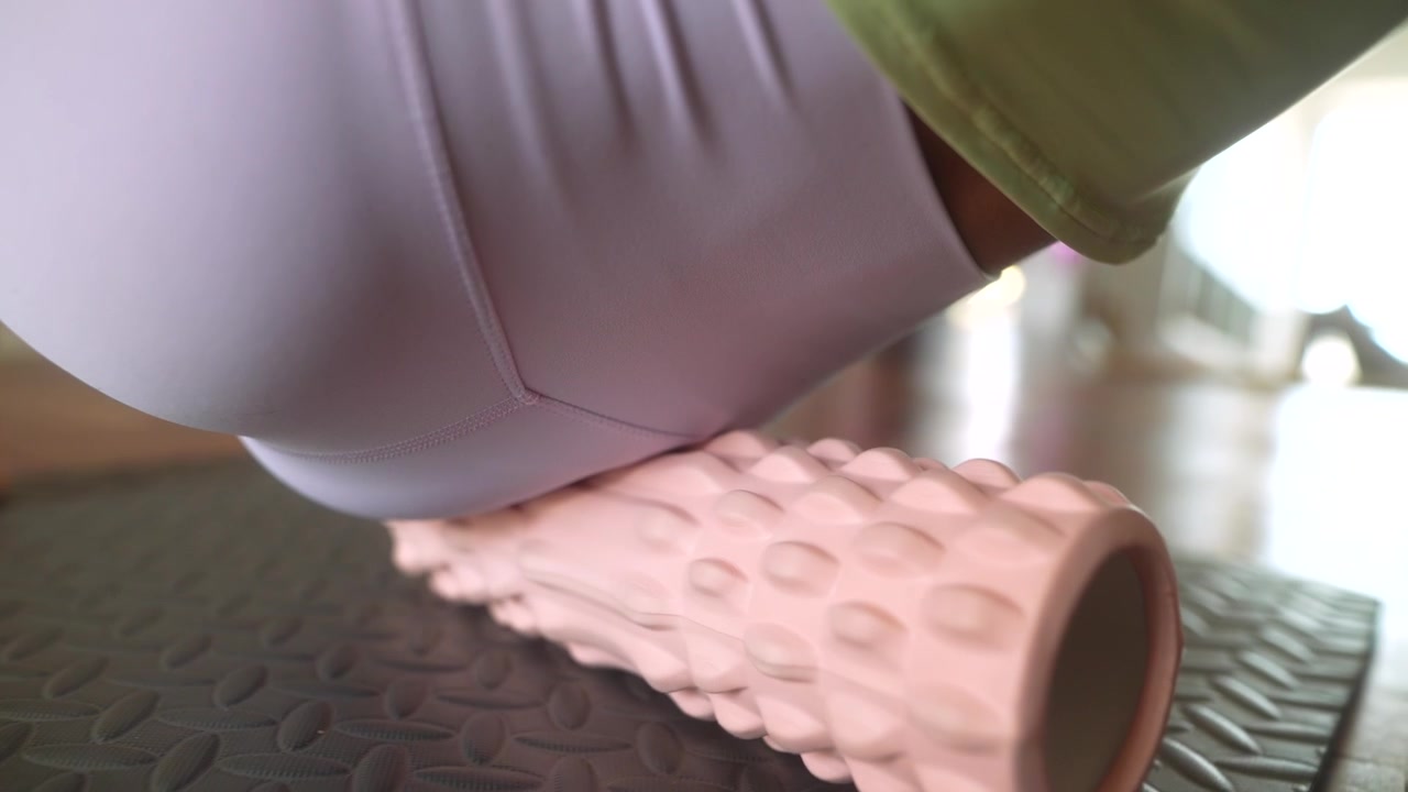 Woman Using Foam Roller for Muscle Recovery on Exercise Mat