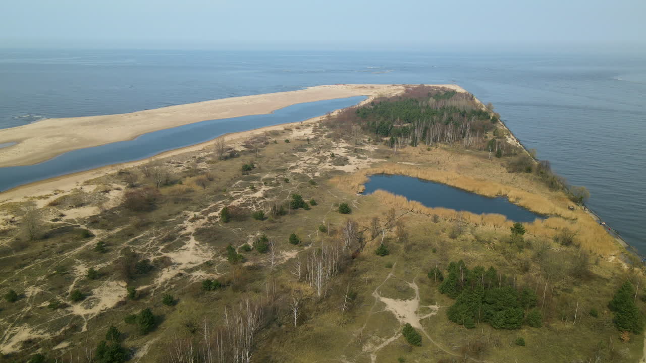toma aérea en movimiento hacia atrás de la reserva natural de mewia lacha durante un día soleado y el mar báltico azul en el fondo, polonia