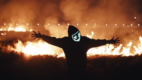 person in mask amidst a field fire at night