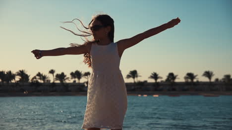 Mujer-Joven-Alegre-Bailando-En-La-Arena-Por-La-Noche.-Chica-Adolescente-Divirtiéndose-En-La-Playa.