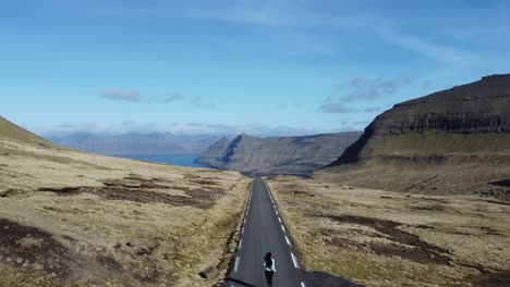 Mujer-Joven-Corriendo-En-Medio-De-Una-Carretera-Escénica-En-Las-Islas-Feroe