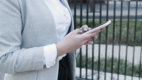 Closeup-view-of-female-hands-using-phone-while-walking-on-street