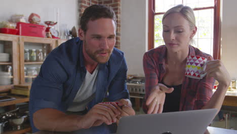 young couple using a laptop in kitchen, close up, front view, shot on r3d