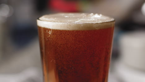 Close-up-of-beer-pouring-into-a-pint-glass-and-bubbles-rising-in-it-4K