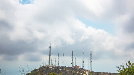 Timelapse-De-Densas-Nubes-Cumulonimbus-Que-Se-Desarrollan-Y-Barren-A-Lo-Largo-De-La-Cima-De-Una-Colina-Sobre-Torres-De-Telecomunicaciones