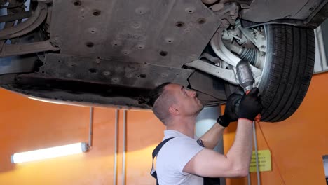 mechanic inspecting car undercarriage with flashlight
