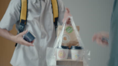 courier delivering food order to female customer paying with credit card