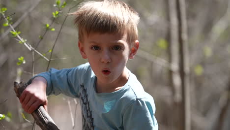 little boy playing with a stick outdoors in the forest, slow motion