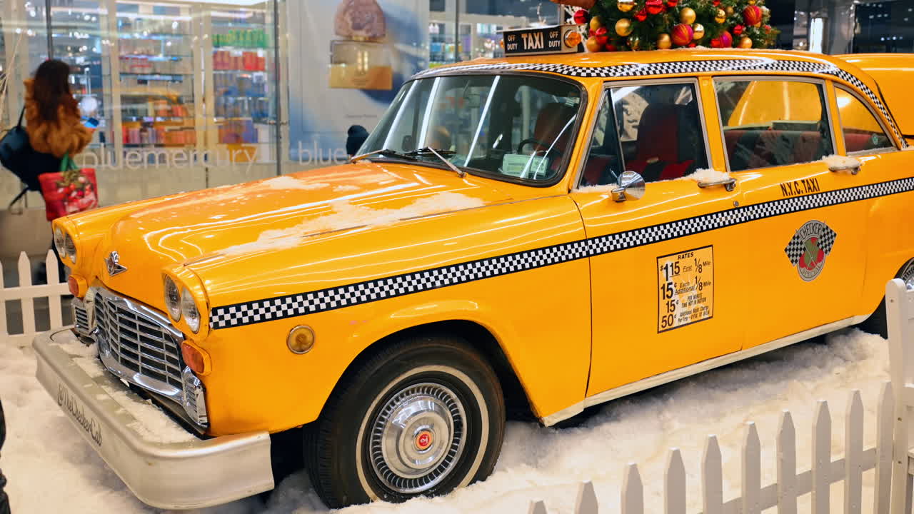 New York, USA, 5. Dezember 2025: Seitenansicht eines klassischen Checker Taxis in winterlicher Umgebung. Vollständiges Seitenprofil des klassischen gelben Checker Cab, umgeben von einem weißen Zaun und in einer simulierten Schneelandschaft.