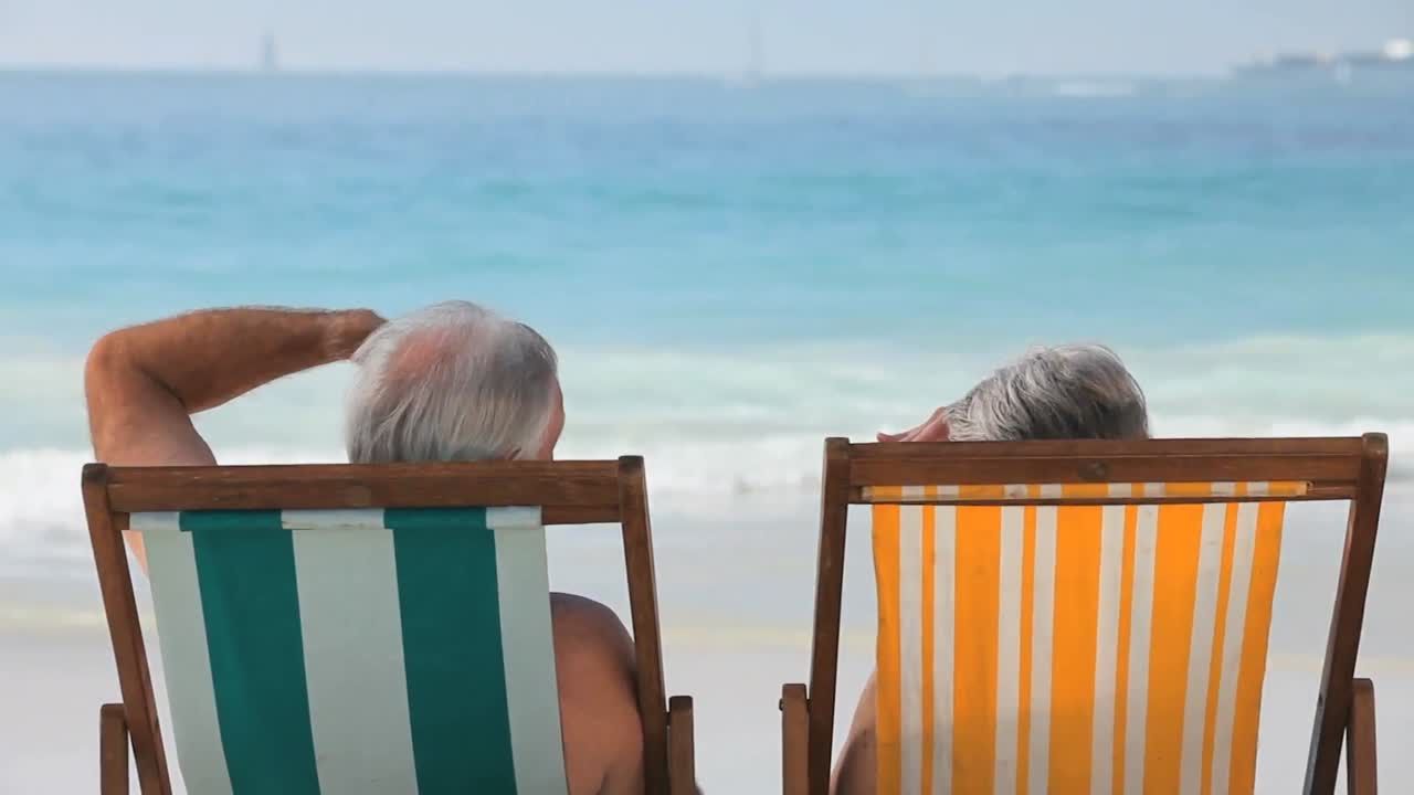 pareja de ancianos mirando el océano sentados en sillas de playa