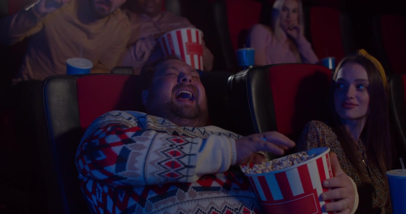 Man Laughing While Watching a Movie in a Cinema