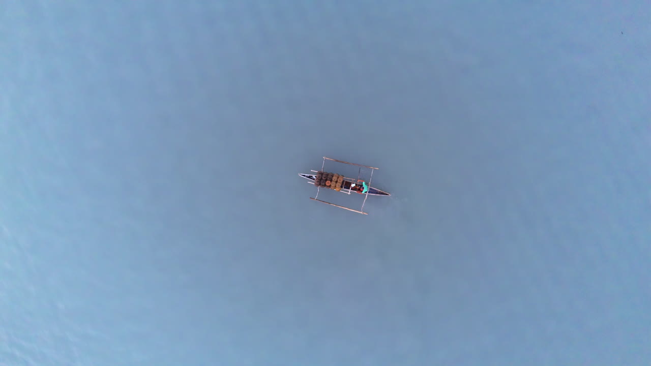 Riser helix drone shot over a local fisherman paddling his small outrigger boat with crab traps at Malampaya Inner Sound