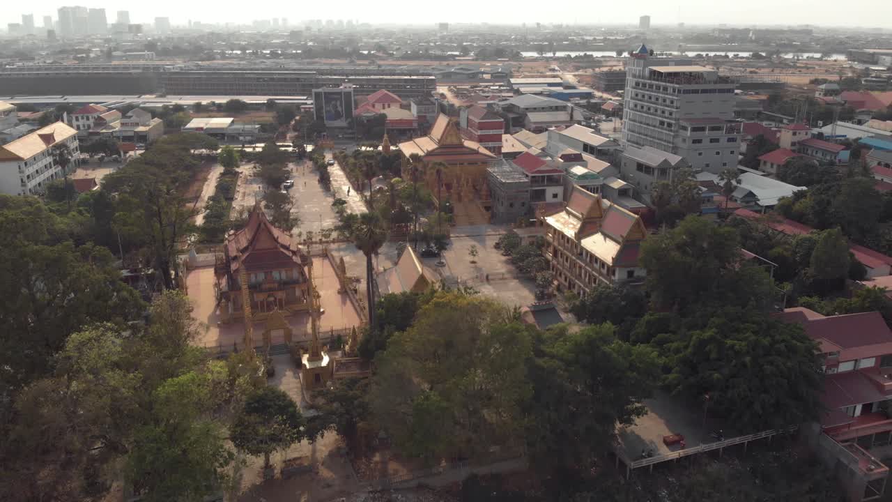 vista desde la orilla del río mekong hasta el templo dorado de phnom penh en medio del paisaje urbano - tiro aéreo amplio sobrevuelo