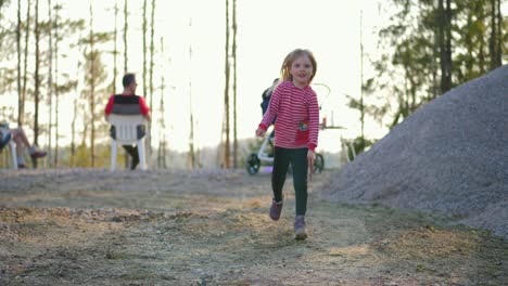 static, slow motion shot of a little blonde girl running in a finnish forest, with a stick in her hand, on a sunny spring day, in vaasa, ostrobothnia, finland