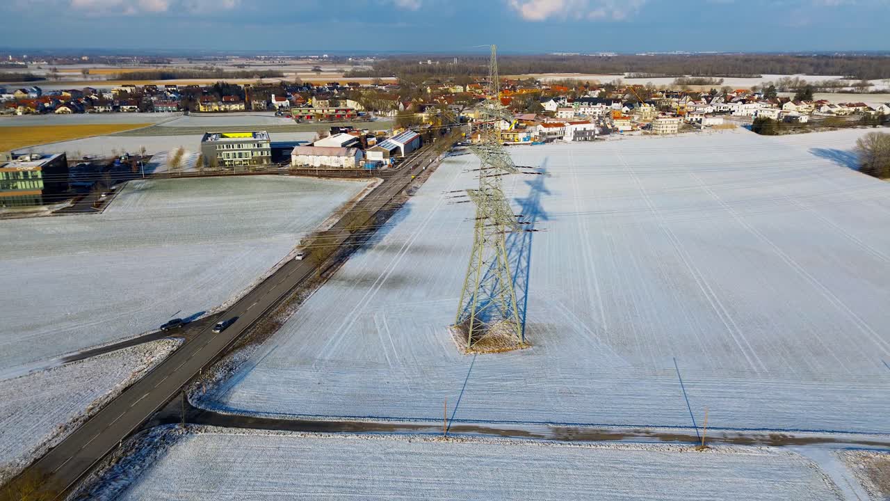 Wintry Village Panorama with Snow Fields and Central Electricity Pylon