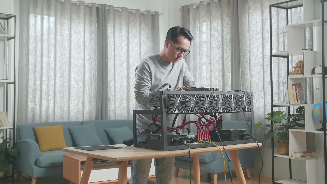 안경을 쓴 아시아인 남자가 암호화폐를 채굴하기 위해 채굴 기계를 만들었습니다.