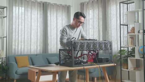 hombre asiático con gafas construye la plataforma de minería para la minería de criptomonedas