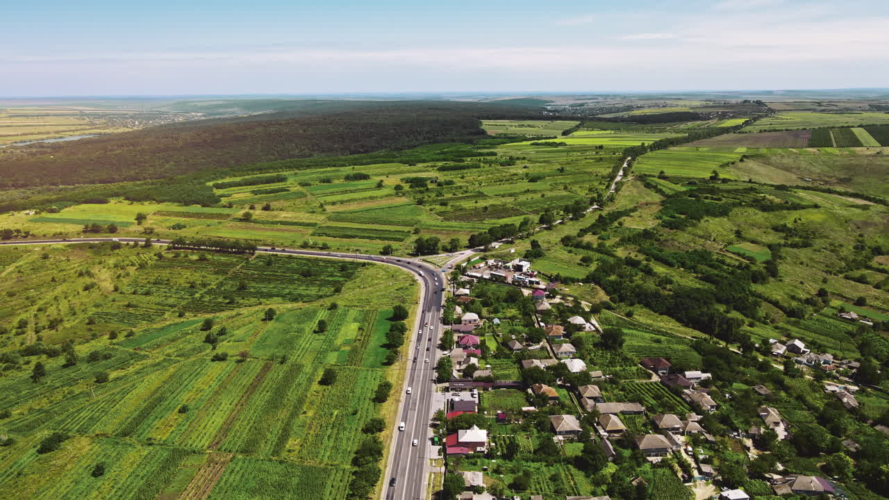 Aerial drone view of a village and road with cars. Greenery, hills and fields in Moldova