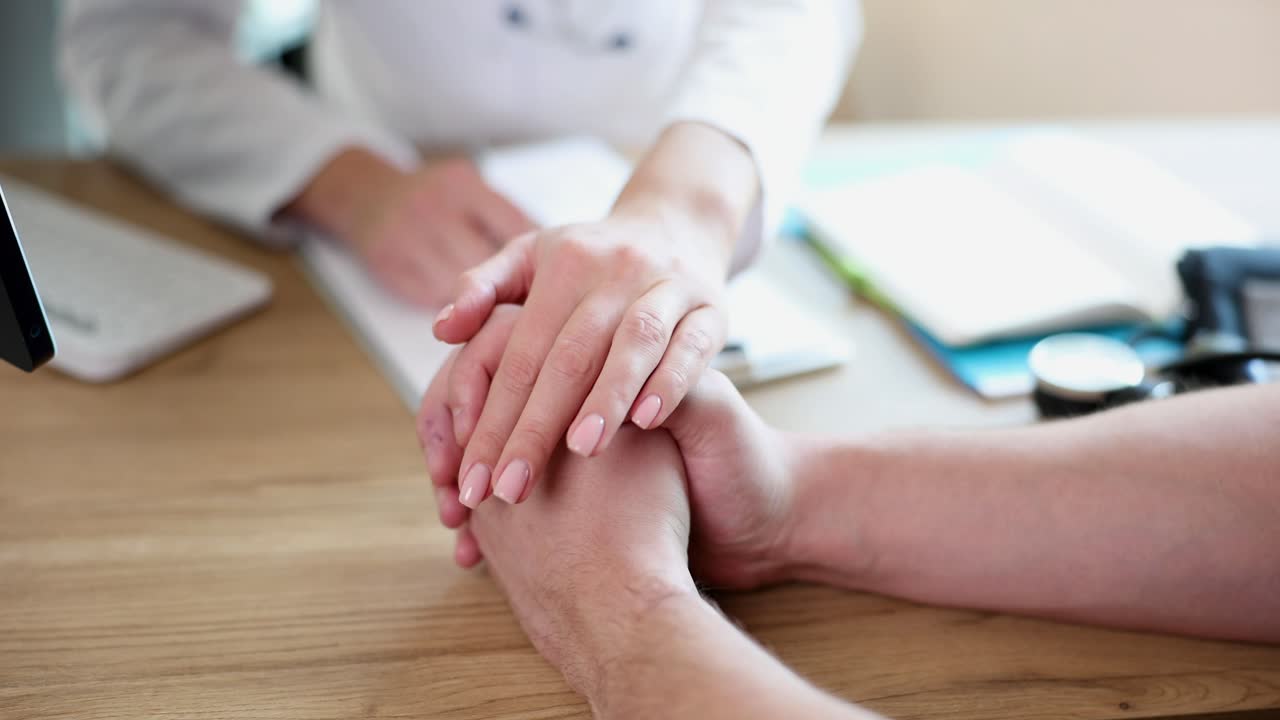 Naislääkäri, terapeutti ja onkologi osoittavat myötätuntoa, tukea ja empatiaa potilaan kättä pidellen.