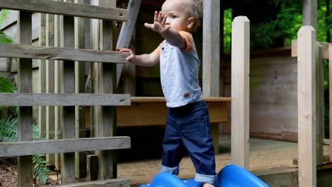 baby jongen staat in de buurt van de glijbaan in het speelhuis 4k