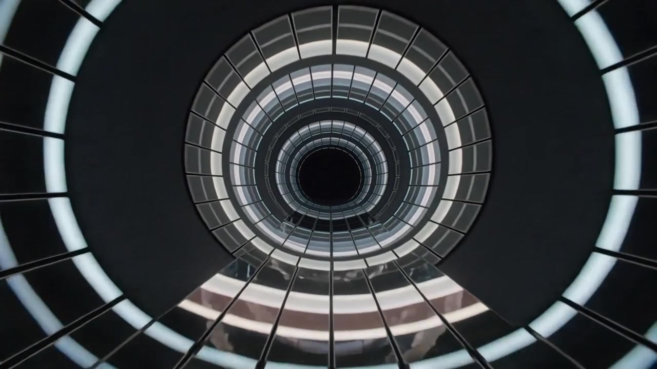 Telecamera che si inclina rivelando un pozzo centrale nell'atrio, mostrando anelli LED e riflessi per il design.