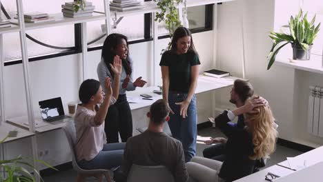 surprised diverse teammates clapping hands, celebrating success.