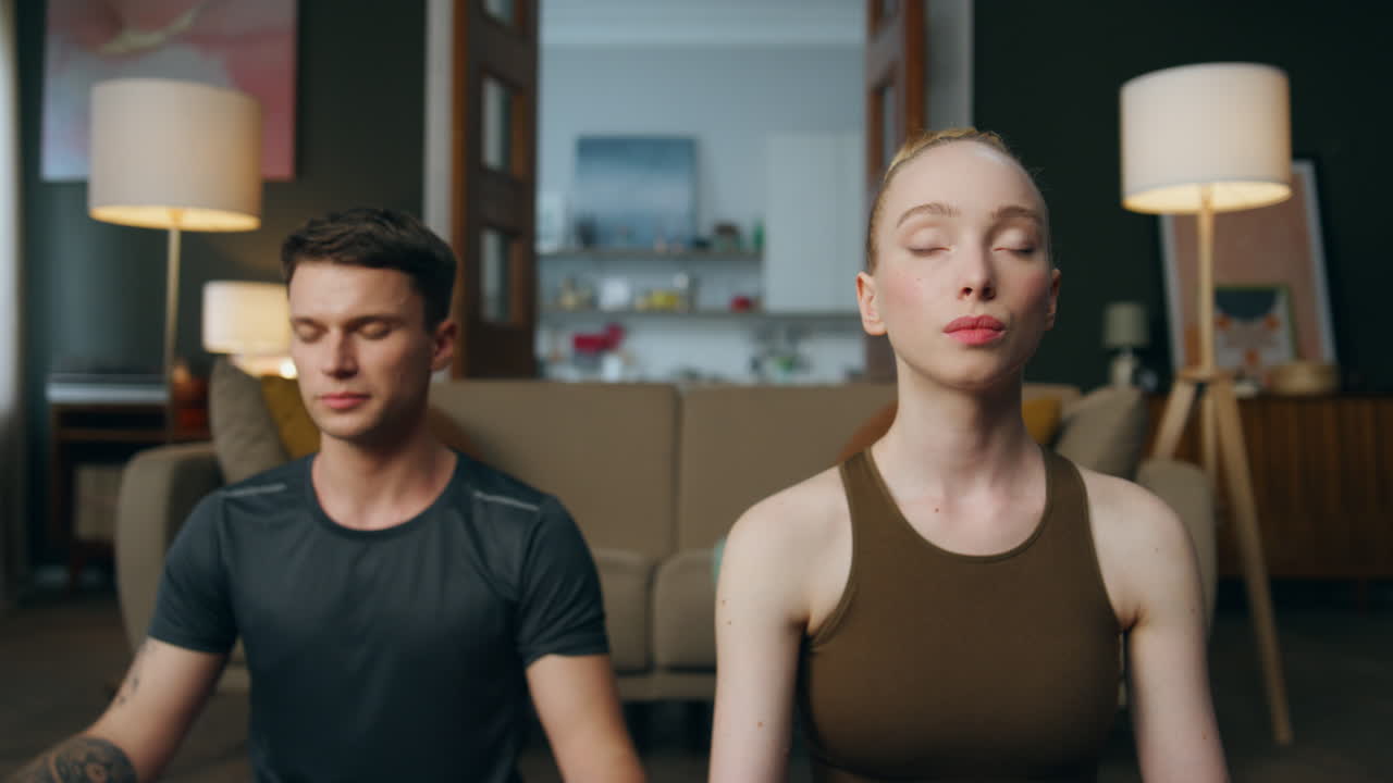 집에서 로터스 포즈에 앉아 숨을 는 연습을 하는 가족.