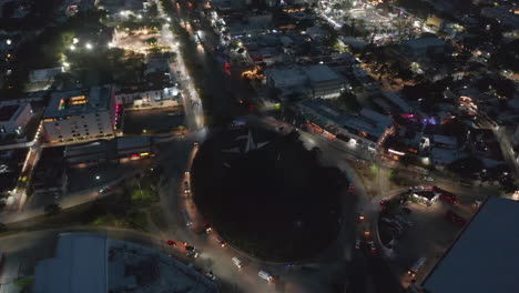 High-angle-view-of-cars-driving-on-large-roundabout.-Fly-above-night-city-with-illuminated-streets.-Cancun,-Mexico