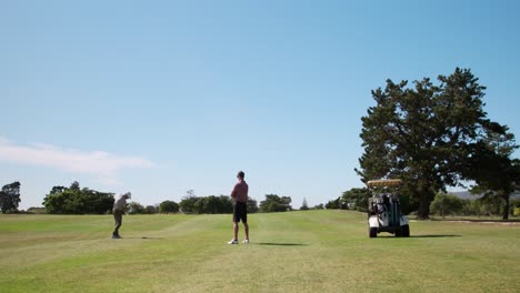 caucasian male golfers playing on a golf course on a sunny day