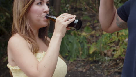 tracking shot of a happy caucasian couple clinking bottles of beer during a barbecue