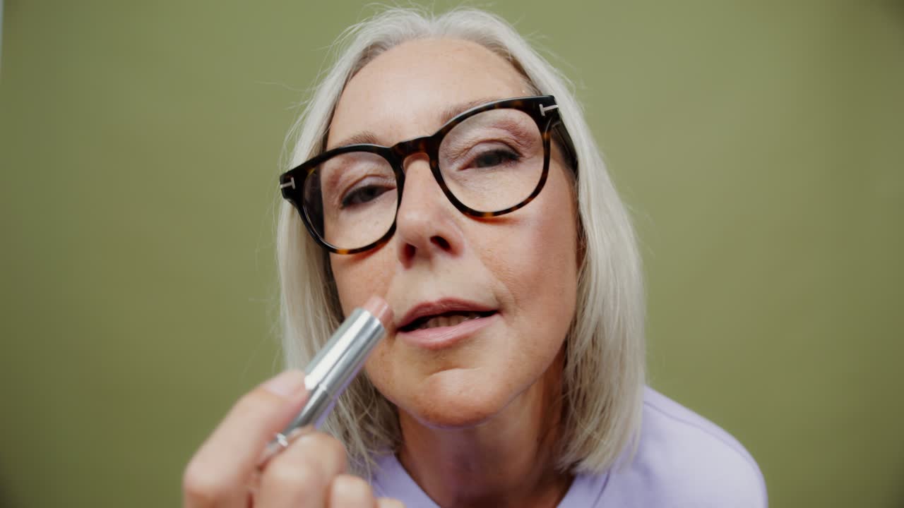 mujer mayor aplicando lápiz labial