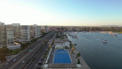 aerial slider shot flying front-to-back over coronado, san diego, california, facing naval amphibious base pool during sunset over pacific ocean
