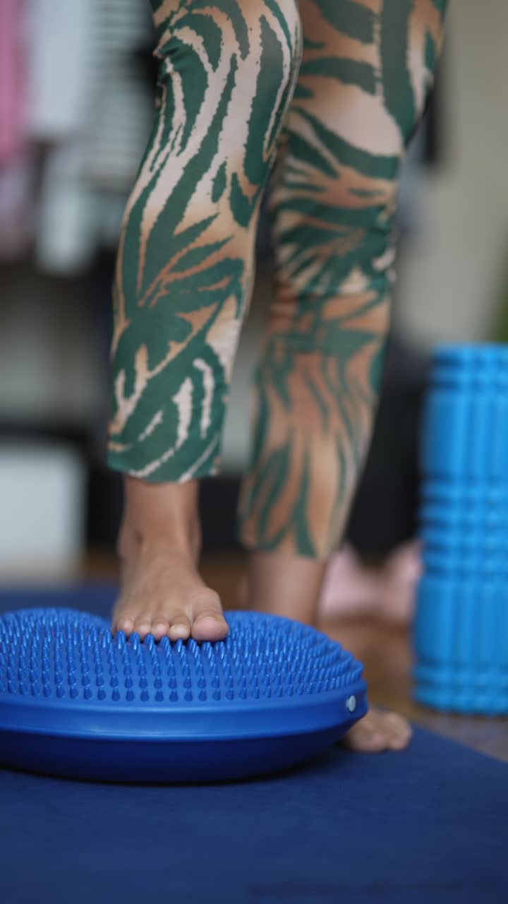 mujer practicando ejercicios de equilibrio en un cojín oscilante
