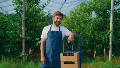 Junger-Bauer-Zeigt-Beerenernte-In-Der-Sommersaison-Im-Obstgarten-Plantagenhaus.