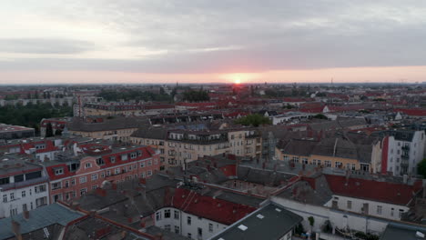 Revelan-Hacia-Atrás-De-Las-Casas-En-El-Barrio-Urbano.-Volar-Por-Encima-De-Las-Calles-Y-Edificios-De-La-Ciudad.-Vista-Contra-El-Sol-Naciente.-Berlín,-Alemania