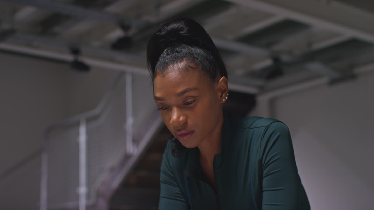 retrato de una atleta decidida entrenando en el gimnasio sentada y concentrada en el vestuario con expresión enfocada