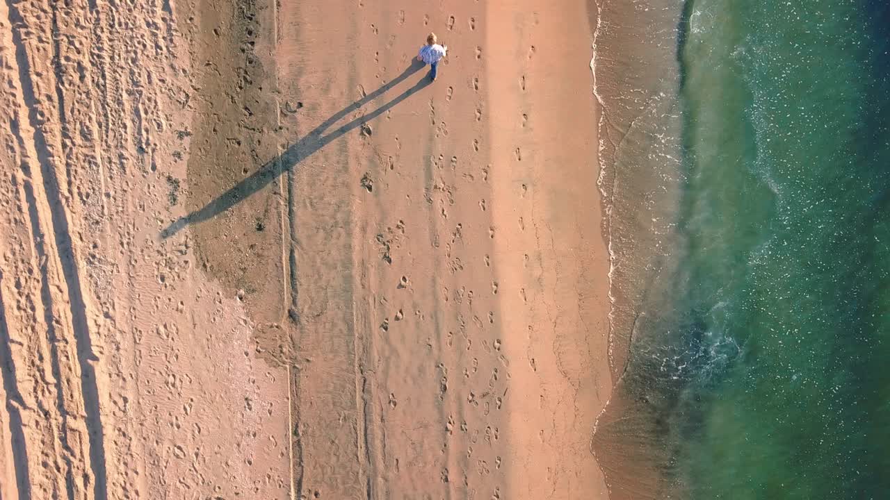 Top down view of person walking on beach during sunset