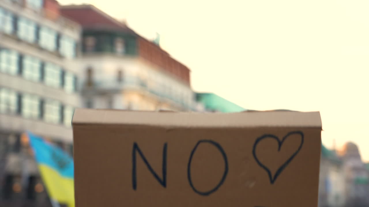 프라하 집회에서 머리 위로 제기된 전쟁에 반대하는 골판지 현수막 항의