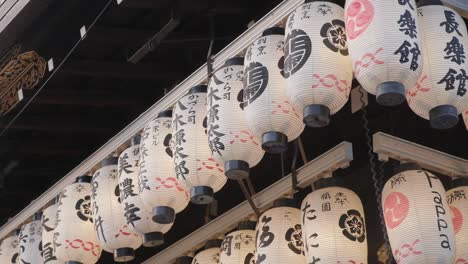 Japanese-lanterns-with-symbols-lit-up-and-swaying-in-breeze-at-New-Years-event-at-Yasaka-Shrine,-Kyoto