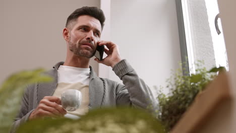 man drinking tea and talking on phone