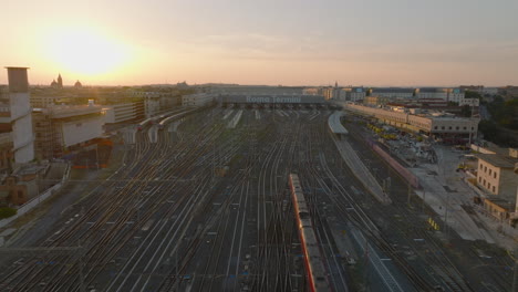 Fly-over-modern-passenger-train-approaching-Roma-Termini-train-station.-Aerial-view-against-colourful-sunset-sky.-Rome,-Italy
