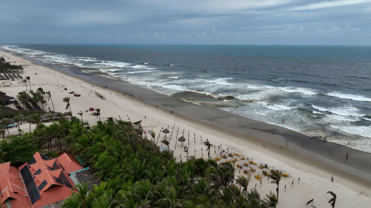 Strong ocean waves roll onto Fortaleza’s expansive sandy beach under cloudy skies