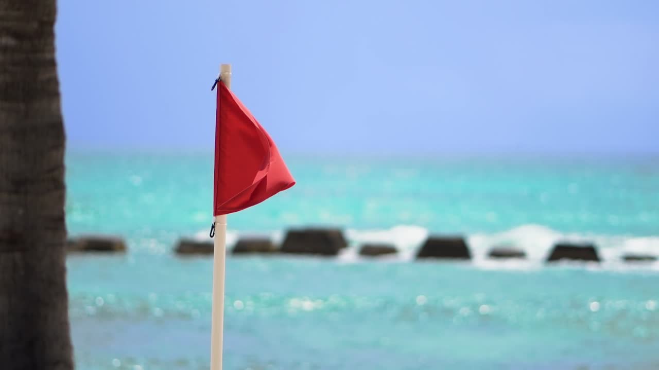 bandera roja ondeando en el viento en una playa tropical